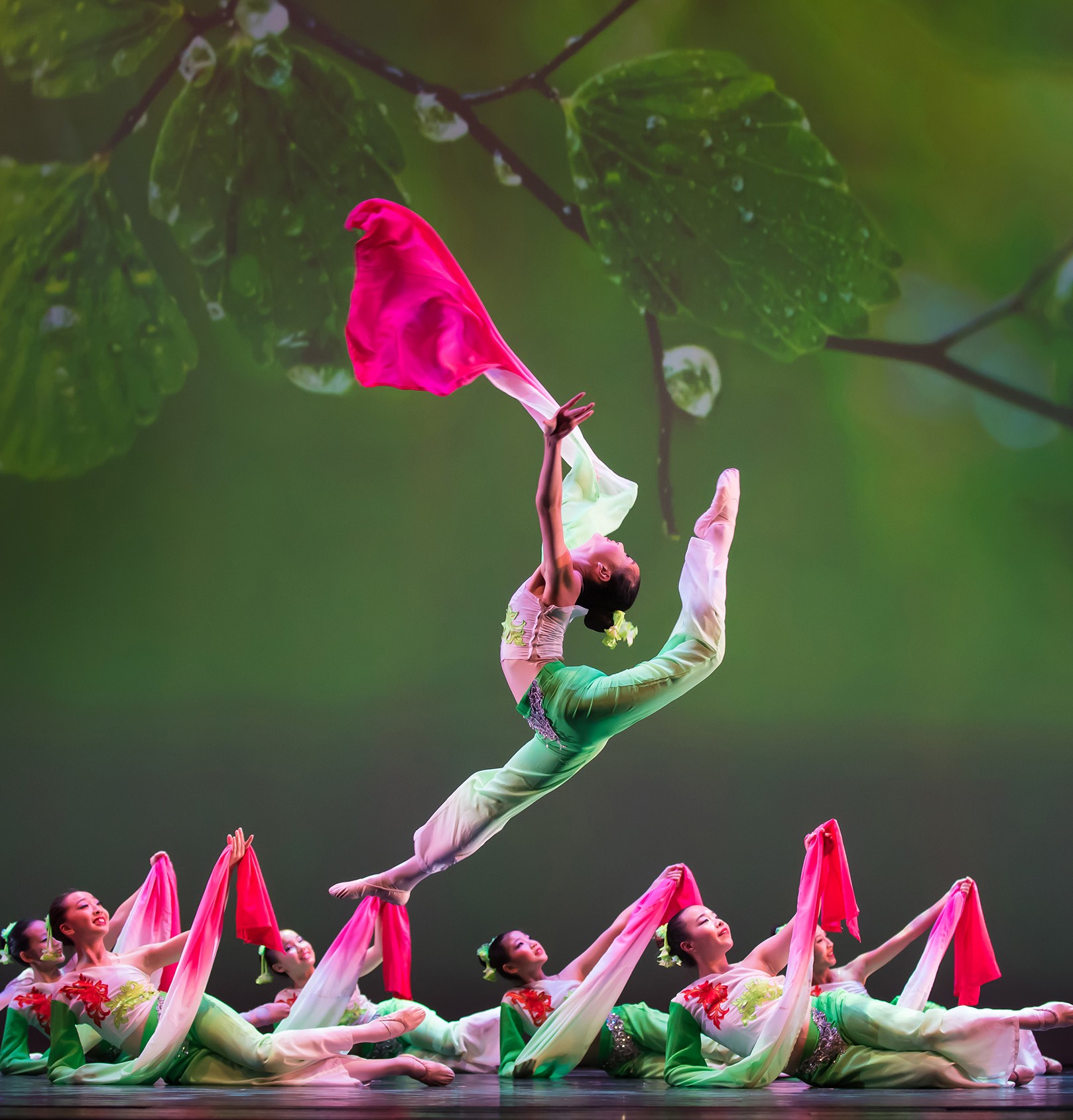 Photo of a silhouette of 2 dancers posing in front of a red curtain.