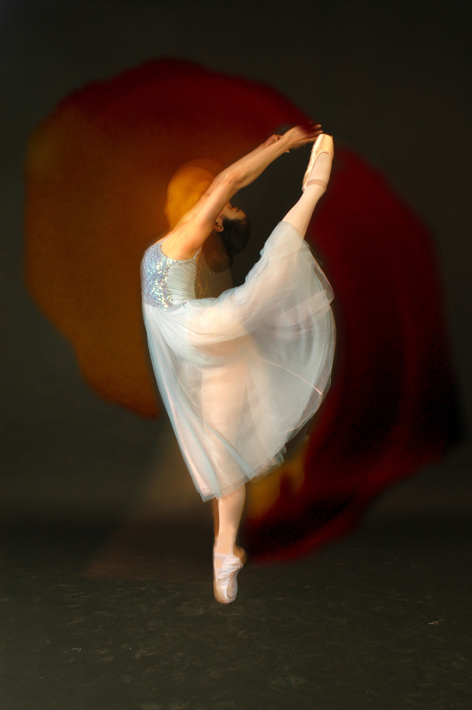 Black and white portrait of a dance instructor posing in front of a dark background.